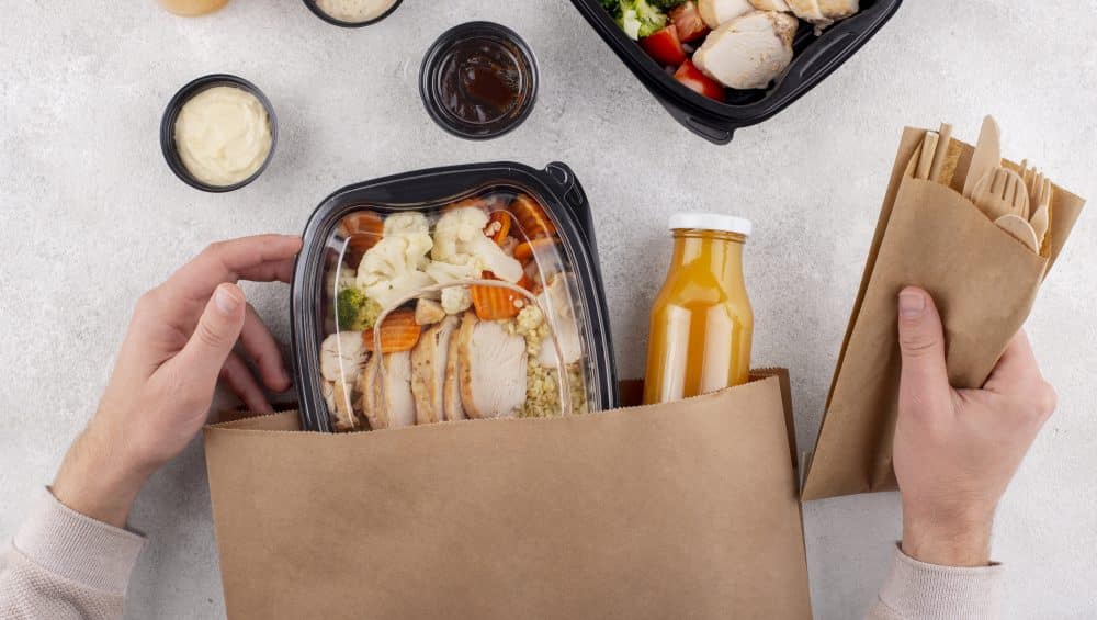 close up hands holding food pack and cutlery