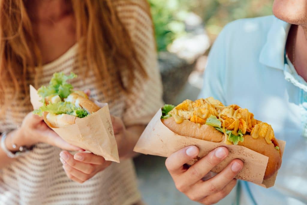 young woman man holding hot dog hands eating street food
