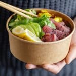 jeune homme tenant bol thon cru sain legumes servis dans bol papier